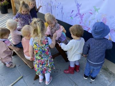 Børn, der maler på en papirrulle på husmuren